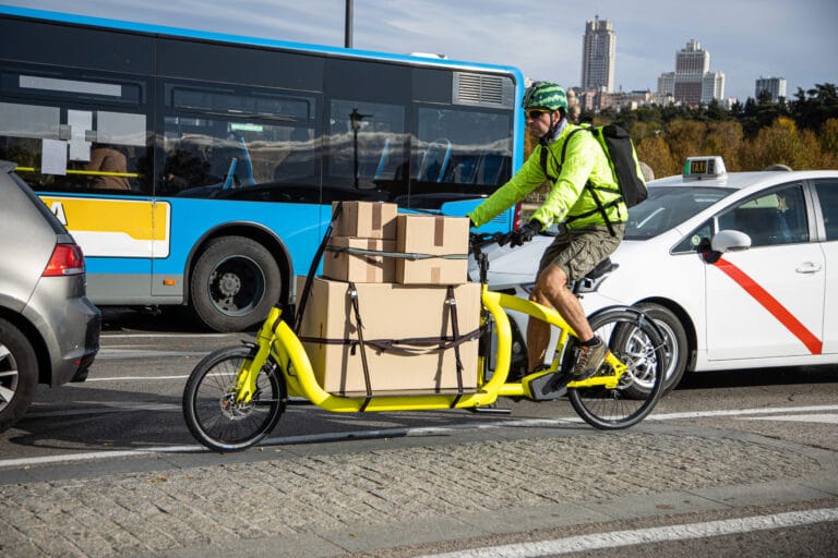 courier traveling with his cargo bike through the city, lateral view